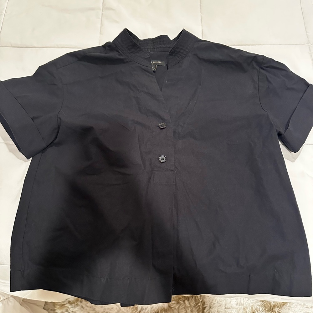 Black pleaded shirt that has half way buttons